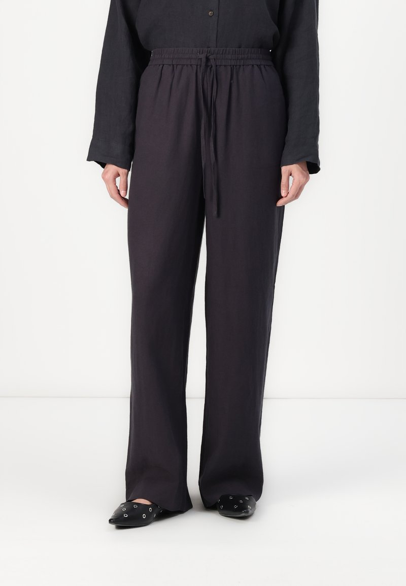 Dark, loose-fitting pants with an elastic waistband and drawstring. Made of a lightweight fabric, featuring a straight-leg design and minimal texture.