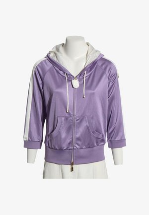 Hellviolette Satin-Kapuzenjacke mit Reißverschluss, weißem Kapuzenfutter, weißen Kordeln, dreiviertel Ärmeln mit weißem Streifen, Fronttaschen, auf Schaufensterpuppe.