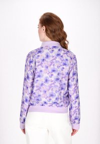 Lichtgewicht bomberjack met een paarse bloemenpatroon, ribgebreide manchetten en zoom, en een effen paarse kraag. Glad, iets glanzend stof.