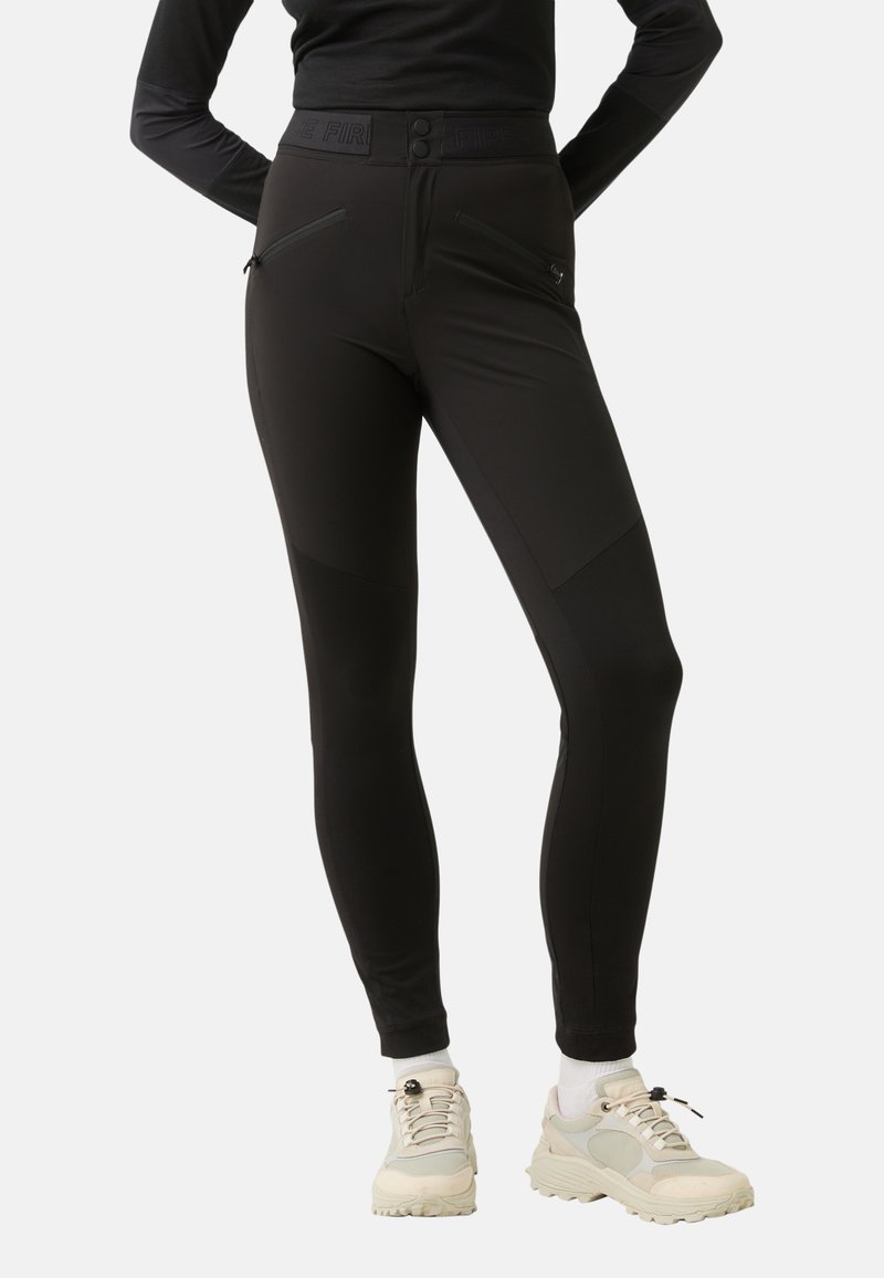 Black leggings with a high waistband, featuring two zippered front pockets, panel detailing, and a close fit. Styled with chunky sneakers.