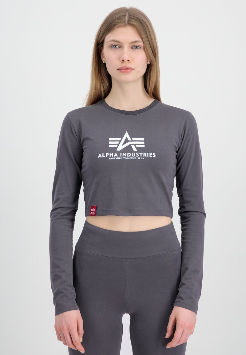 Grå, kortermet langermet topp med hvit logo, rund halslinning og synlig rød etikett; kombinert med matchende høyt midje leggings.
