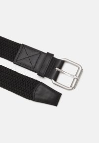 Cinturón tejido negro con hebilla metálica rectangular plateada, acentos de cuero y un diseño de correa texturizada.