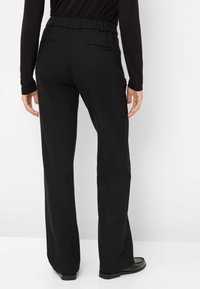 Pantalons noirs à taille élastique avec une coupe décontractée et large. Comprend deux poches arrière et une texture lisse.