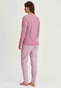 Roze lange mouw top en bijpassende gebloemde broek in een zachte, lichte stof, met een relaxte pasvorm en subtiel textuurontwerp.