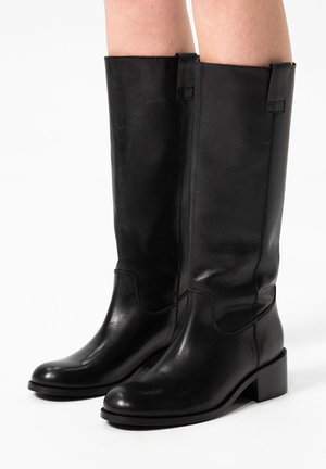 Bottes en cuir noires jusqu'aux genoux avec une texture lisse, des détails de couture subtils et un talon carré. Présente des languettes de tirage en haut.