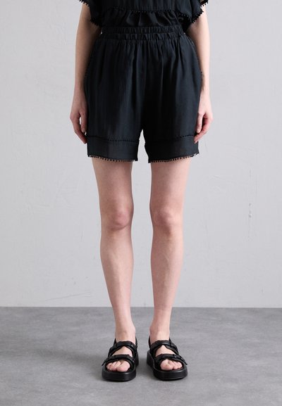 Pantaloni scurți negri dintr-un material ușor, cu talie elastică, având un design în straturi și un bordaj cu pompoane pe margine.