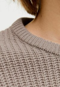 Gestrickter Pullover in hellem Taupe mit einem gerippten Kragen. Verfügt über ein strukturiertes Webmuster und eine lockere Passform, die weiches, dickes Garn hervorhebt.