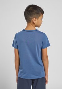 Camisa azul de manga curta com gola redonda, feita de tecido suave. Apresenta um padrão de design discreto nas costas.