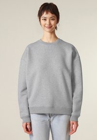 Grijze sweatshirt met een ronde hals, verlaagde schouders, geribbelde manchetten en zoom. Zacht materiaal met een gladde textuur, gecombineerd met lichte spijkerbroeken.