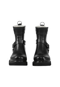 Botas de tobillo de cuero negro con un acabado suave, correas resistentes, hebillas de metal y una lengüeta trasera. Suelas de goma planas completan el diseño.