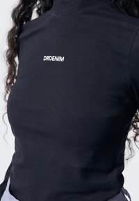 Schwarzes Rollkragen-Shirt aus Baumwolle mit weißem, gesticktem "DRDENIM"-Logo auf der Brust und einer figurbetonten Silhouette.