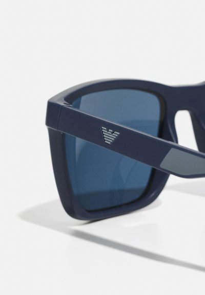 Ochelari de soare bleumarin cu lentile întunecate, design cu ramă pătrată, finisaj mat și un logo în accente argintii pe lateral.