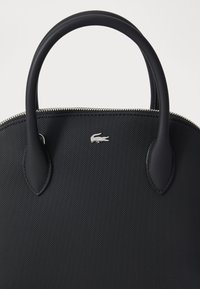 Sac à main en tissu noir texturé avec deux poignées rondes, fermeture éclair argentée et un petit accent logo argenté.