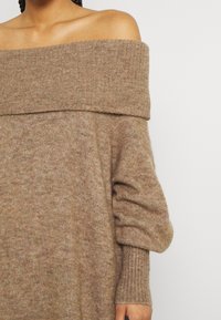 Schulterfreier, gestrickter Pullover aus weichem, braunem Stoff. Mit gerippten Bündchen und einem breiten, umgeschlagenen Ausschnitt für eine lässige Passform.