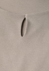 Pletená tkanina v světlé béžové barvě s malým oválným výřezem. Měkká textura, těsný steh a minimální vzor po celé délce.