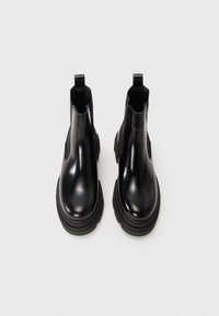 Bottes de cheville en cuir noir avec une finition lisse, des panneaux latéraux élastiques et une semelle en caoutchouc épaisse, dotées de languettes à l'arrière pour un enfilage facile.
