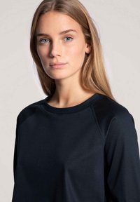 Black sweatshirt with a round neck and raglan sleeves. Smooth texture, minimal stitching details, fitted design.