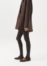 Blazer oversize marrone, collant a coste marrone scuro e ballerine marrone scuro con fibbia. Concentrati sui contrasti di texture e colore.