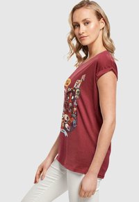 Maron bomulds t-shirt med rullede korte ærmer, med et farverigt grafisk design af tegneseriefigurer på forsiden. Ensfarvet bagside.