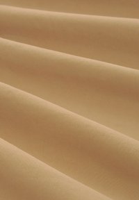 Miękka, teksturowana tkanina w ciepłym beżu z delikatnymi fałdami. Jednolita powierzchnia bez wyraźnych wzorów czy akcentów metalowych.