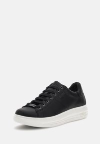 Sneaker in pelle nera con suola in gomma bianca, caratterizzato da una punta arrotondata, lacci frontali e logo in rilievo sul lato. Design semplice.