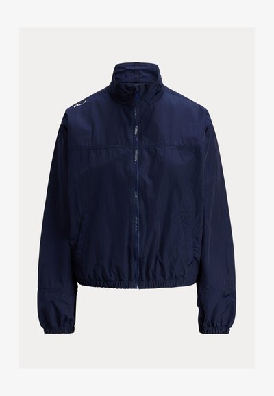 Marineblå vindjakke med høy krage, glidelås foran, elastiske mansjetter og sidelommer. Lett, teksturert stoff.