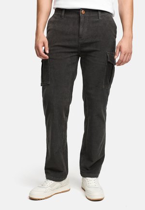 Sorte corduroy cargobukser med to sidelommer, en frontlukning med knap og en afslappet pasform, parret med hvide sneakers.