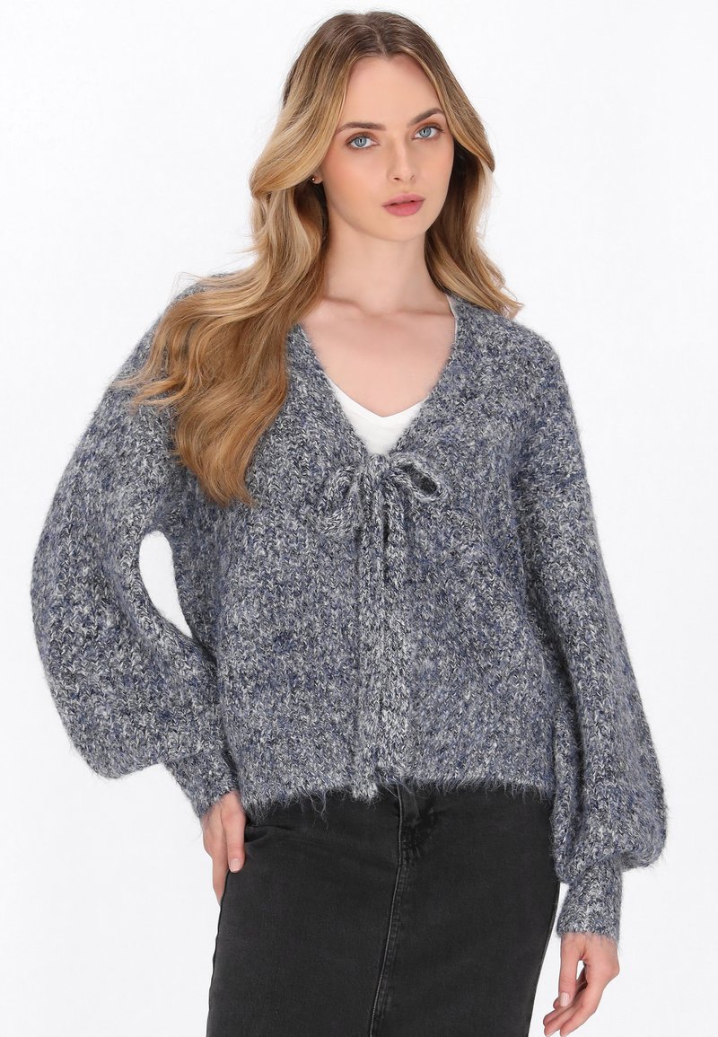 Cardigan grigio lavorato a maglia con una consistenza morbida, caratterizzato da un profondo scollo a V, chiusura anteriore legata e maniche voluminose.