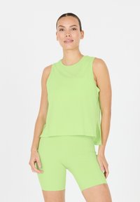 Ljusgrön ärmlös topp med rundad halsringning, ihop med matchande cykelshorts. Mjukt tyg och avslappnad passform, minimal detaljering.