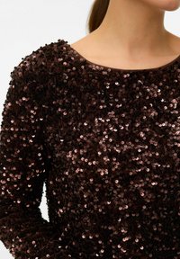 Brūns garām piedurknēm sequined tops ar apaļu apkakli, kas izrotāts ar cieši izvietotām vara krāsas spīdīgām aplikācijām un gludu faktūru.