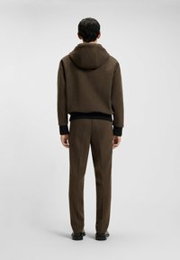Bruine hoodie met een textuurafwerking, voorzien van een capuchon, geribbelde manchetten en tailleband, gecombineerd met bijpassende bruine broeken. Minimalistisch ontwerp.
