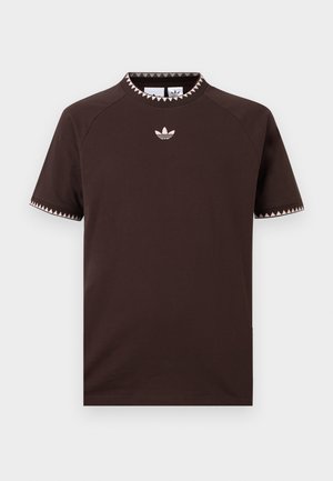 Camiseta de manga corta color marrón oscuro con ribete triangular rosa claro en el cuello y las mangas, con un pequeño logo de trébol de Adidas centrado en el pecho.
