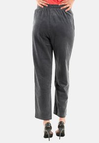 Pantalones de pana gris con una textura acanalada, cinturilla elástica y un diseño de pierna recta, combinados con zapatos de tacón alto negros.