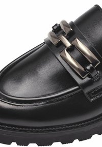 Zwart leren loafer met een gestructureerde afwerking, voorzien van een brede band en een metallic gespaccent. Dikke rubberen zool met een profielpatroon.