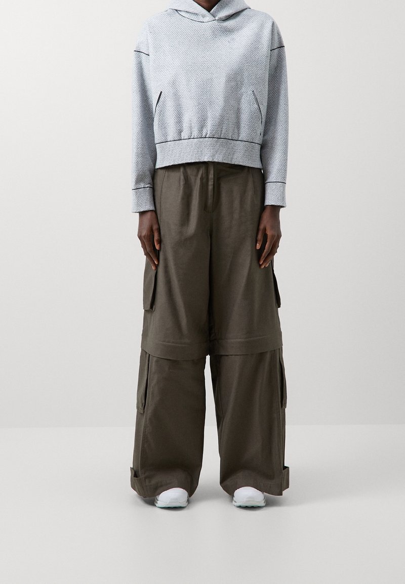 Ljusblå kort hoodie med en texturerad mönster och dragsko, kombinerad med lösa olivgröna cargobyxor med sidofickor.
