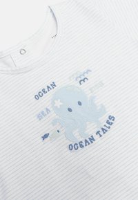 Camisa de manga corta a rayas de color azul claro, con un diseño de pulpo bordado acompañado de texto, fabricada en tejido suave y con cuello redondo.