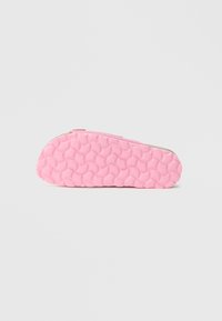 Ružová podrážka sandále s textúrovaným kruhovým vzorom, bočný pohľad na jednoduchom svetlom pozadí.
