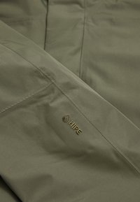 Olive green waterproof fabric with a smooth texture, featuring an embossed gold "HIPE" logo on the upper left side seam.
