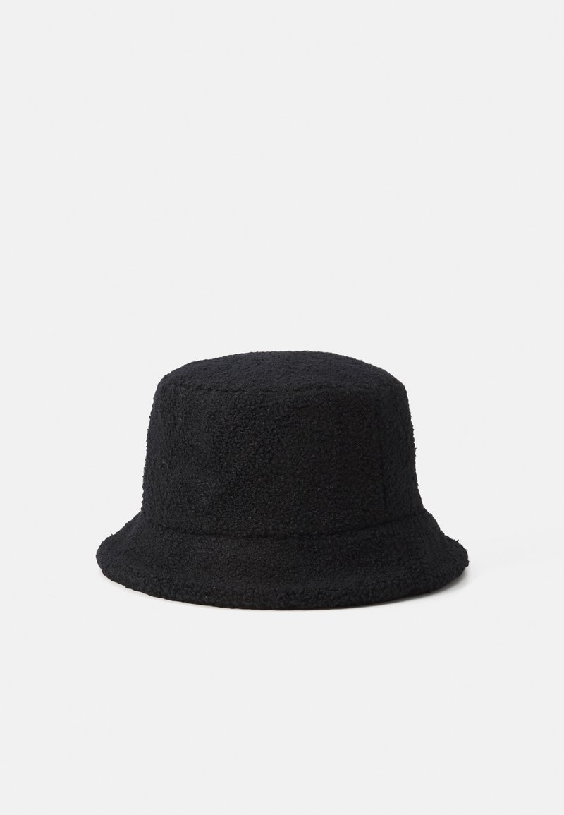 Chapeau seau noir texturé en matériau doux, semblable à de la polaire, avec un bord incliné vers le bas sur un fond blanc uni.