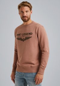 Bruine sweatshirt met een ronde hals en geribde manchetten, met "PME LEGEND AMERICAN CLASSIC" in zwart gedrukt en vleugeldetails.