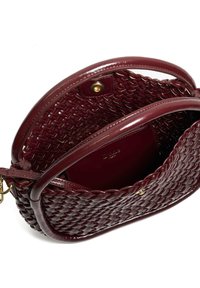Woven burgundy leather handbag with rounded handles, open top, inner pocket, and gold-tone magnetic snap closure.