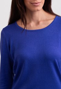 Blauw longsleeve shirt met een ronde hals, gemaakt van een zachte gebreide stof, met een gladde textuur en een getailleerde pasvorm.