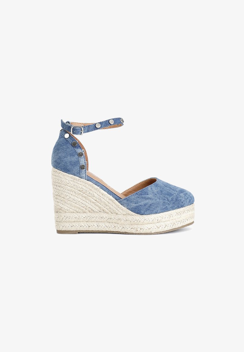 Sandali a zeppa in denim blu con cinturino alla caviglia, caratterizzati da borchie metalliche, una piattaforma in corda testurizzata e un design con punta arrotondata.