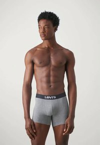 Γκρι βαμβακερά σορτς μποξέρ με μαύρη ζώνη Levi's, εφαρμοστή σχεδίαση και απαλό υφάσμα. Το μοντέλο ποζάρει με τα χέρια χαλαρά στις πλευρές.