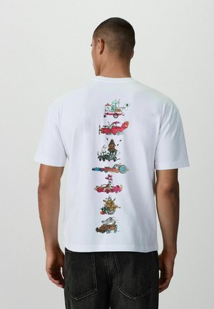 Mann trägt ein weißes T-Shirt mit vertikalen Cartoon-Designs verschiedener skurriler Fahrzeuge und Figuren auf der Rückseite.