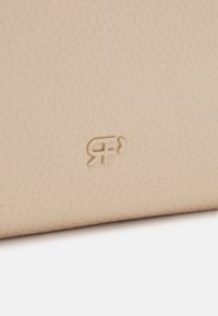 Light beige leather wallet with a textured surface. Featuring a debossed logo in the bottom corner, providing a subtle design detail.