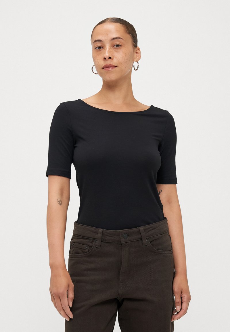Top nero fitted a maniche corte con scollatura ampia, realizzato in tessuto elasticizzato, abbinato a pantaloni marroni scuri a vita alta. Design semplice.