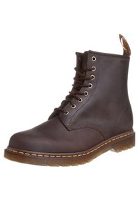Bottine à lacets en cuir marron foncé avec coutures jaunes, semelle rainurée et languette à l'arrière.