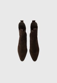 Bottines en daim marron avec un bout pointu, des panneaux latéraux élastiques et une tirette, présentant une texture lisse et un design effilé.