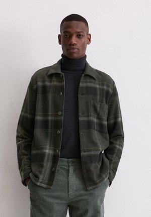 Grijze gestreepte shirtjack in een wolblend met groene en zwarte tinten, met een kraag, knoopsluiting en een borstzak. Gecombineerd met corduroybroek.